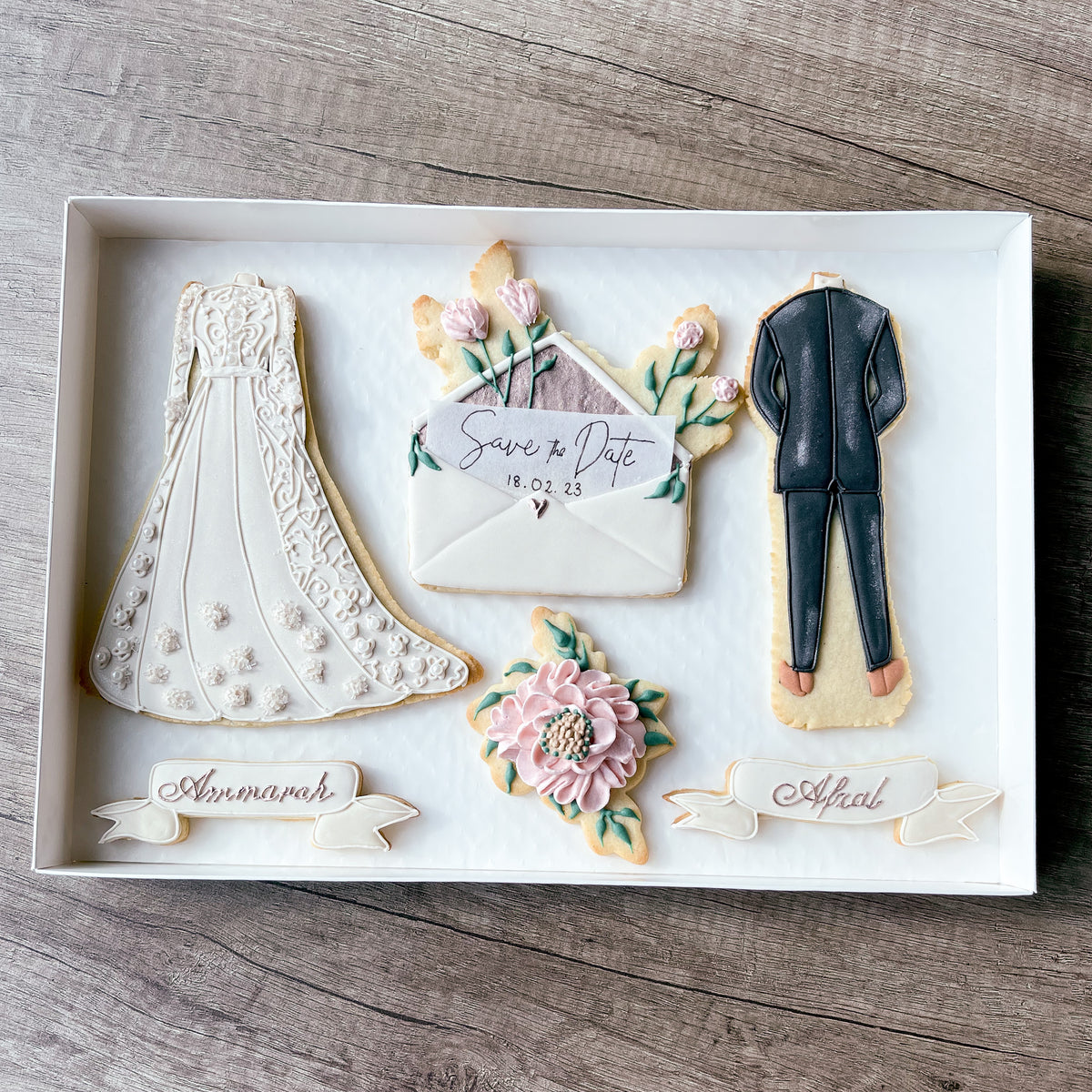 Handmade wedding sugar cookies featuring a bridal dress, suit and floral save-the-date envelope